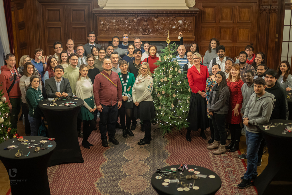 A group of people standing around a Christmas Tree.