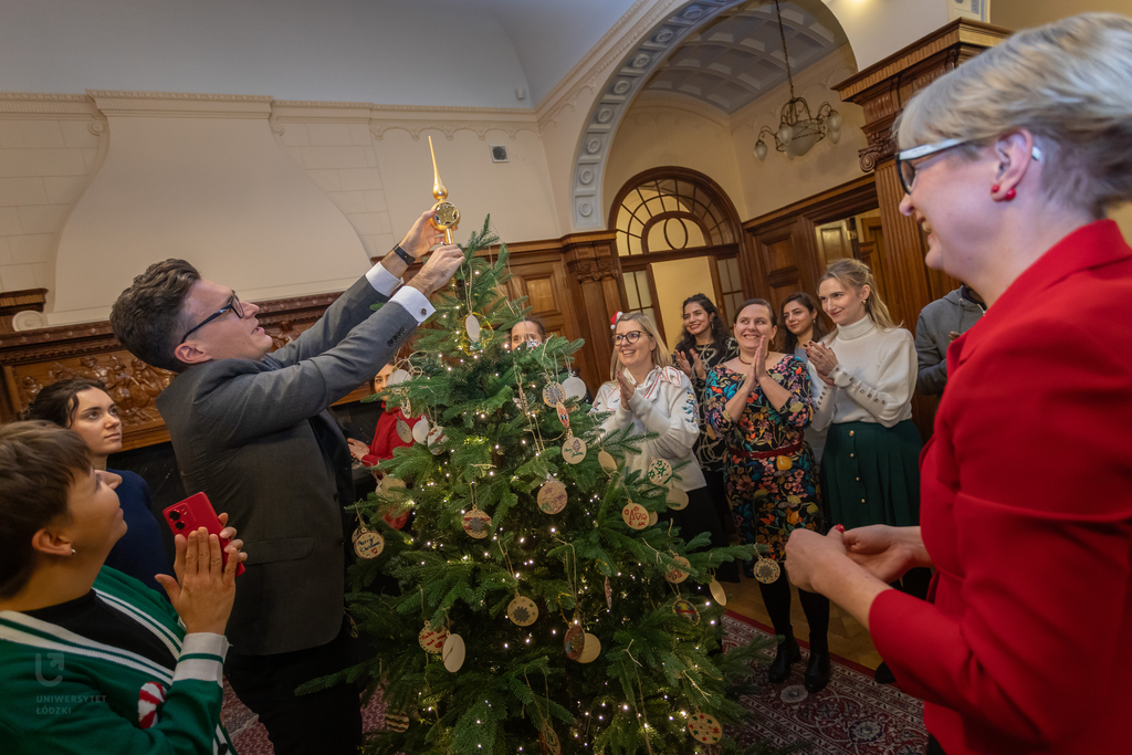People decorating a Christmas Tree.