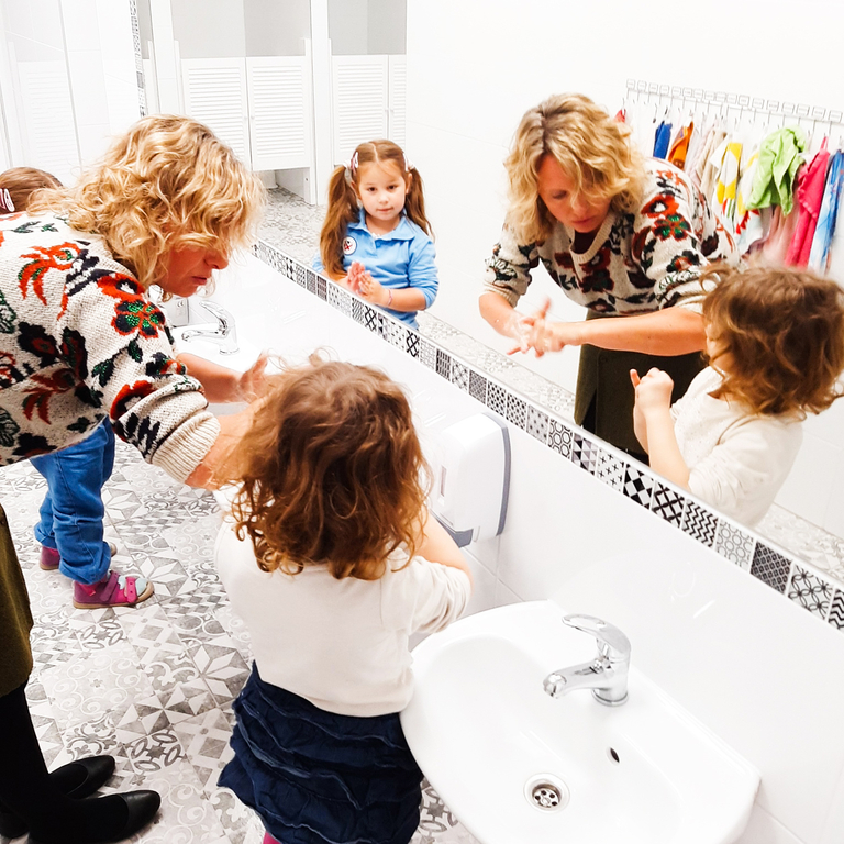 kids and teacher wash their hands
