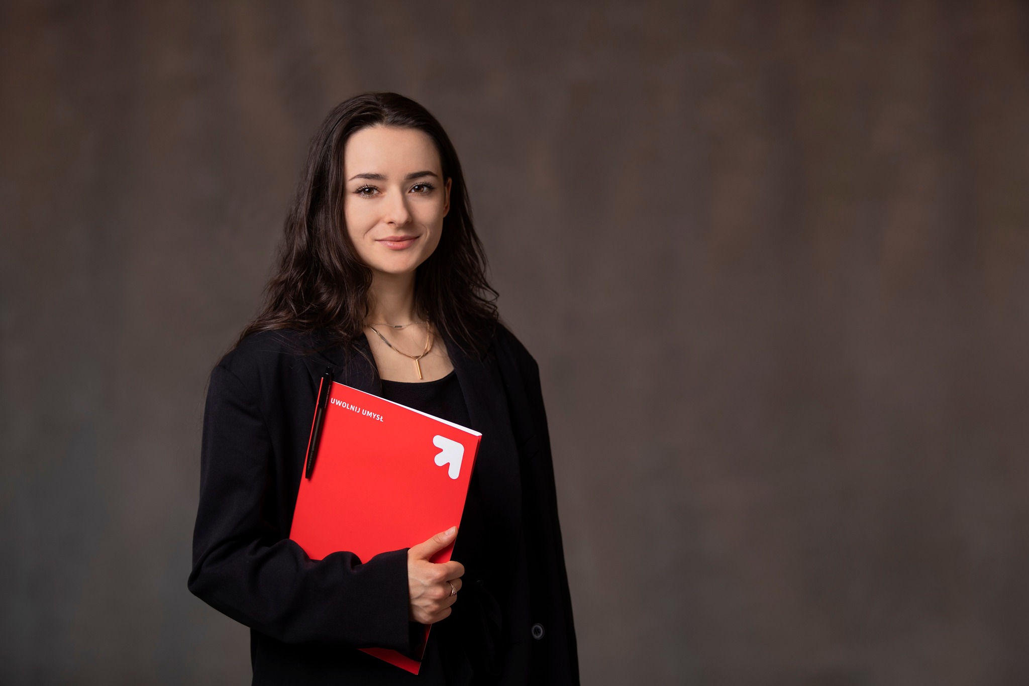 Studentka trzymająca czerwoną teczkę z dokumentami. 