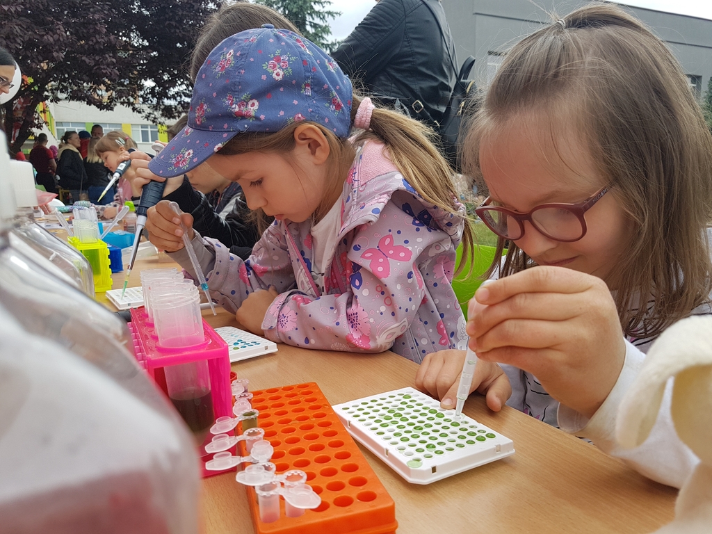 Dwie dziewczynki pipetują kolorowe płyny na pikniku