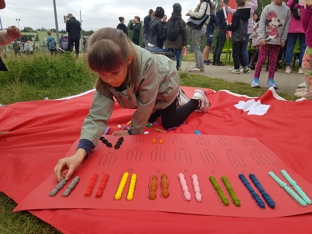 Dziewczynka na pikniku rodzinnym układa układankę z chromosomów