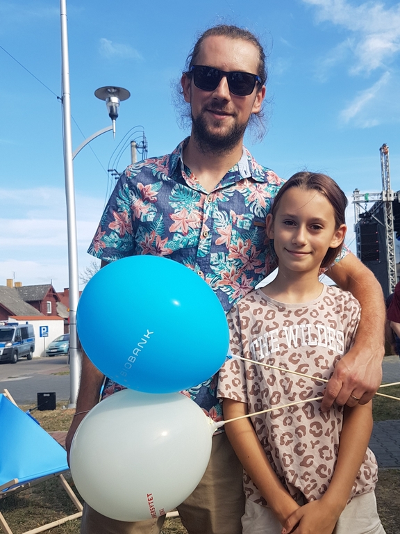 Tata z córką trzymają balony UŁ podczas pikniku