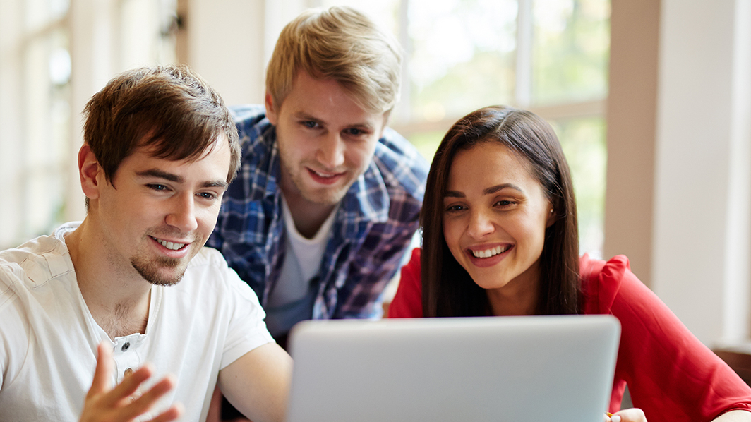Trójka studentów patrzy w ekran laptopa