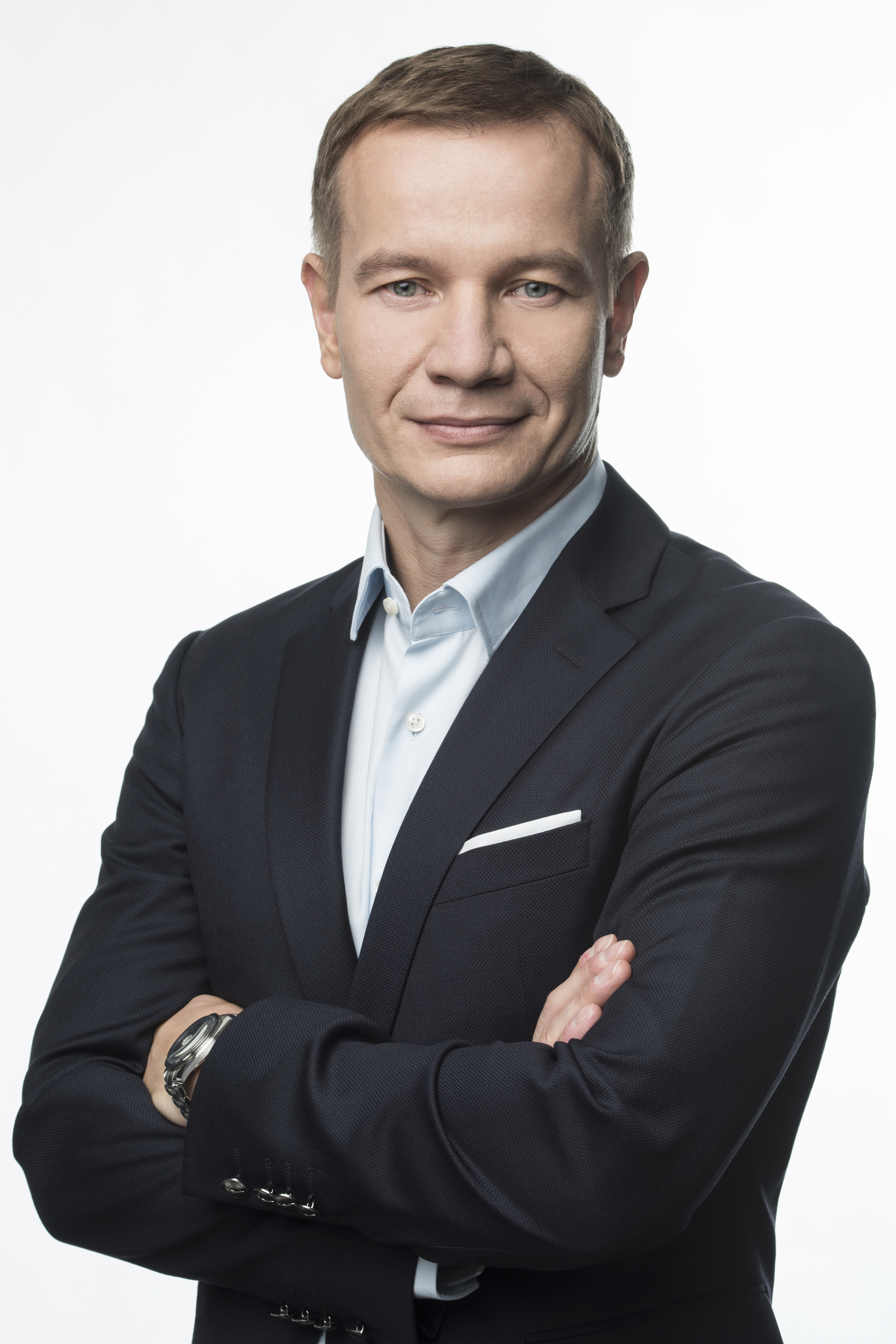 mężczyzna w ciemnoszarym garniturze stoi, ręce założone