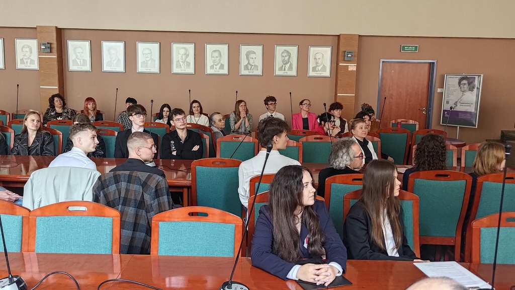 młodzi ludzie siedzą i obserwują z zaciekawieniem 