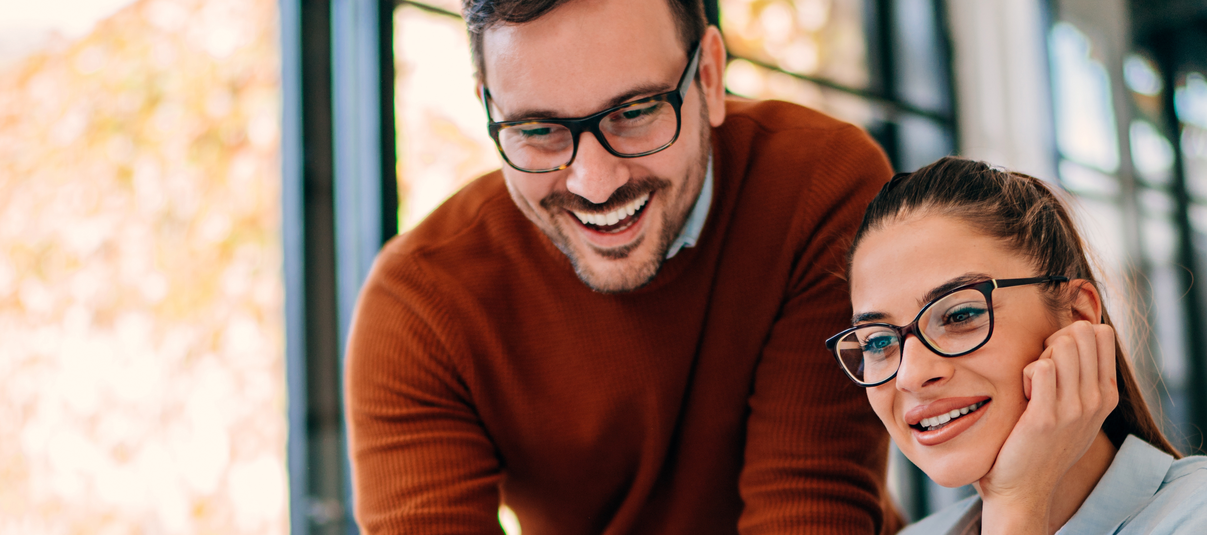 uśmiechnięte osoby nad laptopem