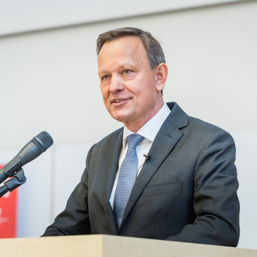 mężczyzna w szarym garniturze mówi do mikrofonu