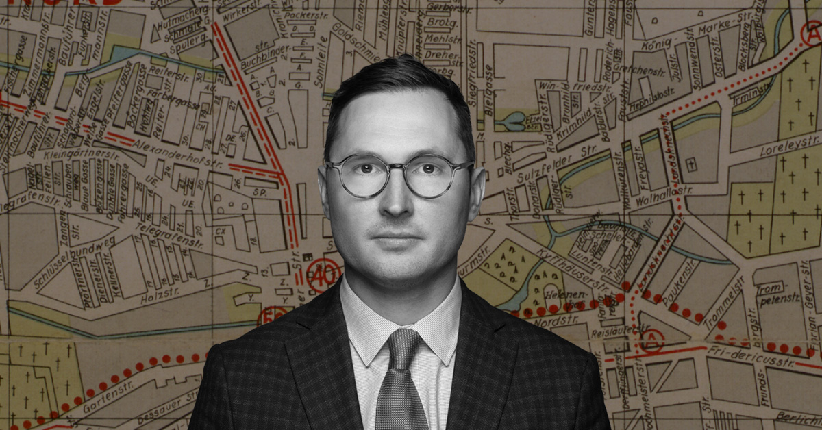 Dr Adam Sitarek na tle mapy łódzkiego getta