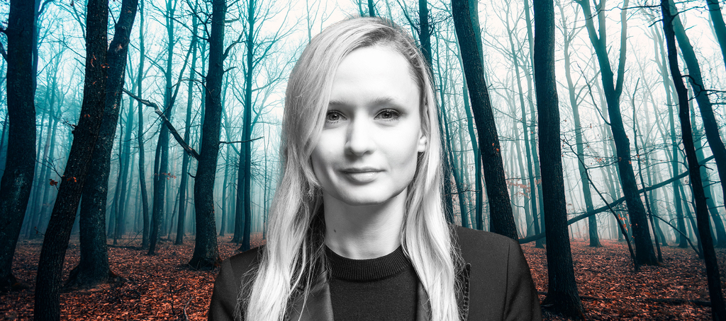 Dr Marta Jablonska against a background of a forest illuminated by bright blue light
