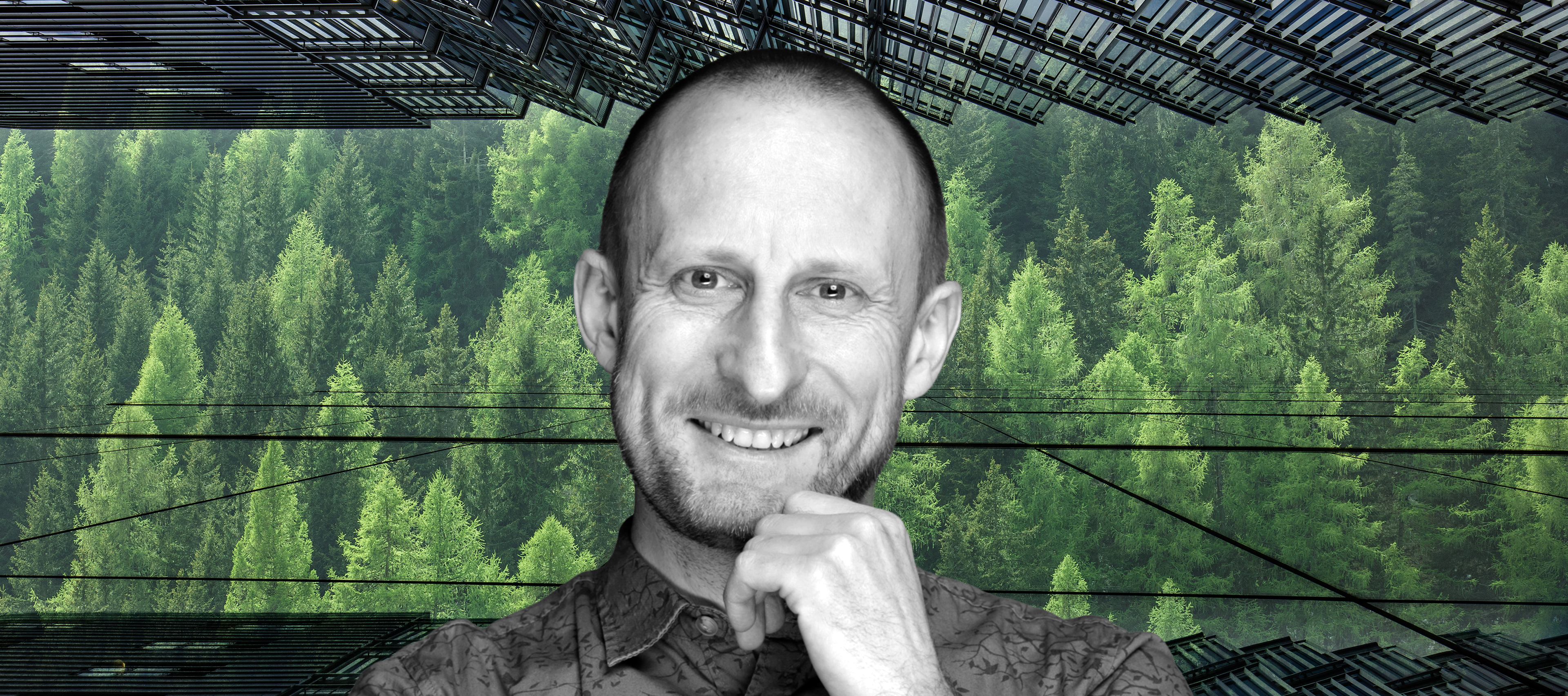 Uśmiechnięty wizerunek profesora Jakuba Kronenberga na tle zielonych drzew, widoczne również szklane fasady drapaczy chmur