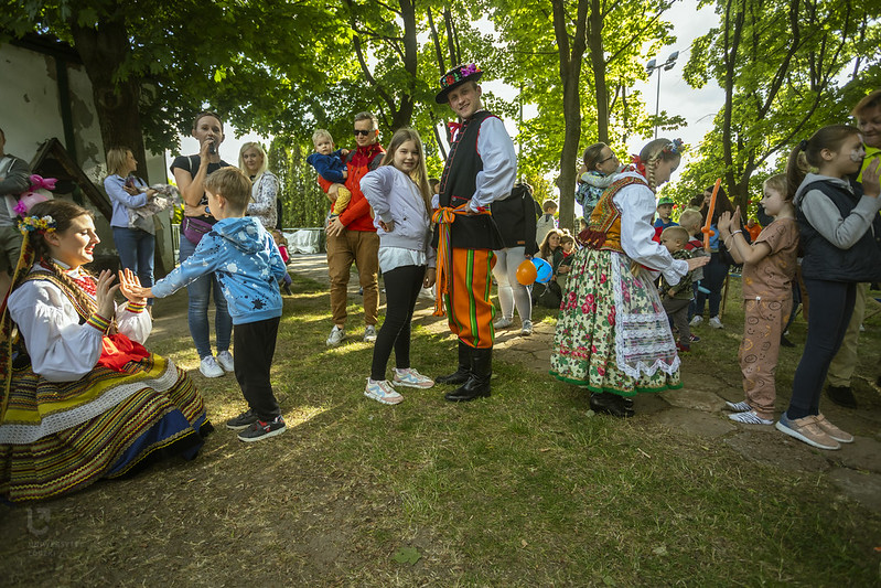 Dzieci i bawiący się z tancerzami AKADEMICKI ZESPÓŁ PIEŚNI I TAŃCA UŁ "KUJON", ubranymi w stroje ludowe